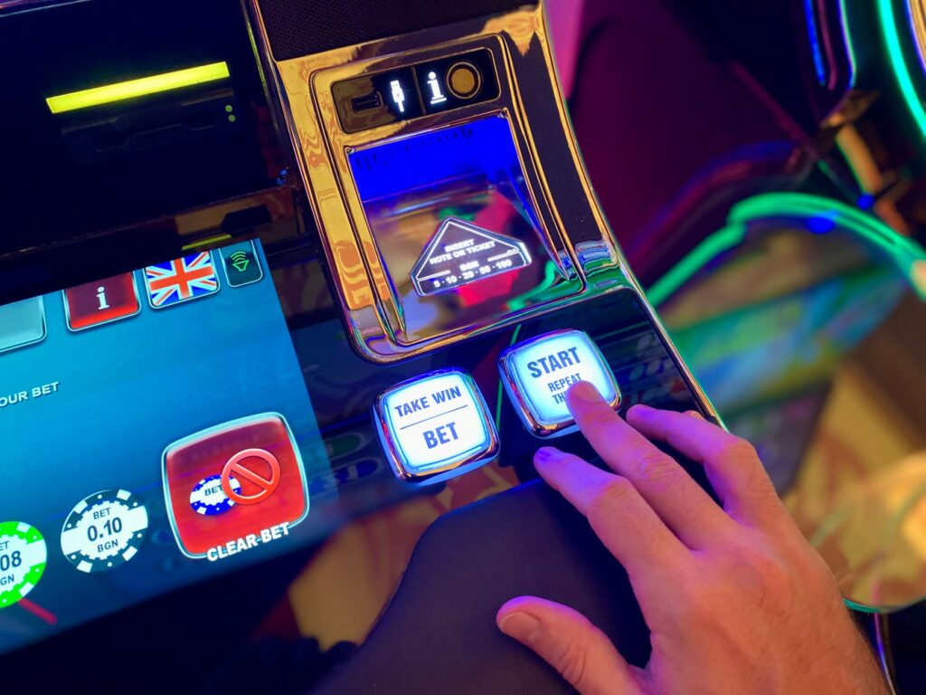 Hand pressing illuminated start button on a casino slot machine screen