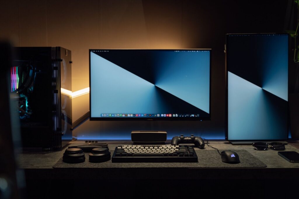 Dark desk with dual monitors and game controller glowing