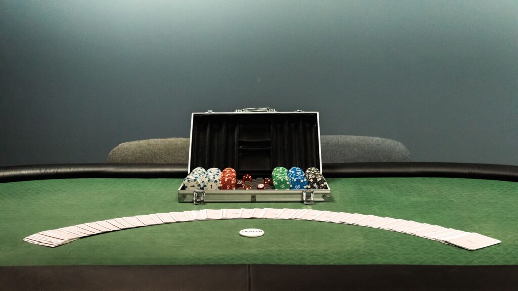 Low-lit poker table with cards and chip stacks in shadow
